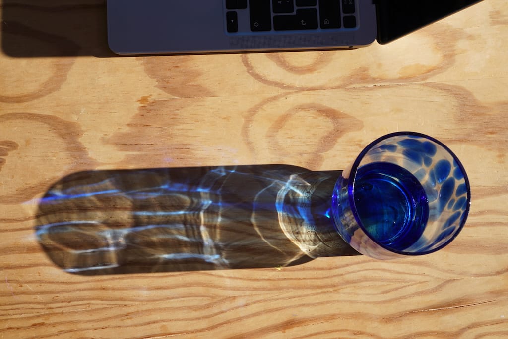 Shadow of a blue-spotted glass in the sun.