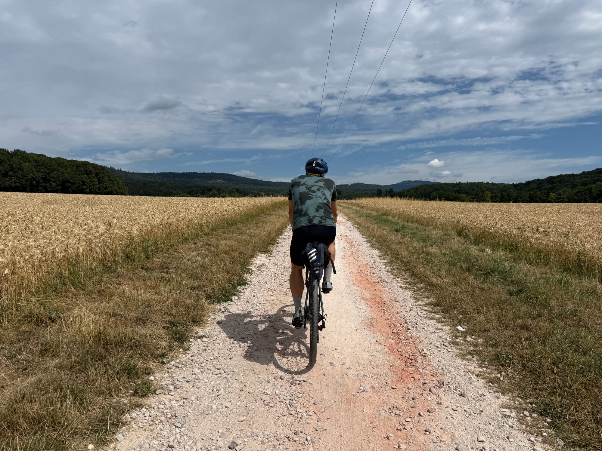 A man wearing the Icon Merino T-Shirt while cycling through corn fields.